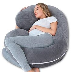 a pregnant woman laying in a large grey bean bag chair with her stomach tucked under the pillow