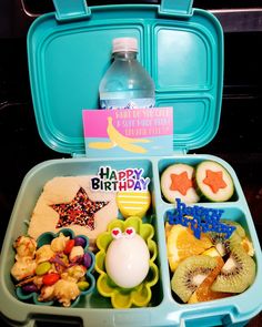 a blue lunch box filled with lots of food next to a bottle of water on top of a table