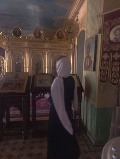 a woman in a nun's outfit walking through a room with paintings on the walls