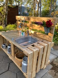 an outdoor sink made out of wooden pallets with flowers in the potted planter