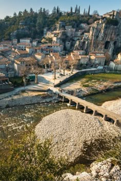 an old town is perched on top of a hill overlooking a river and stone bridge