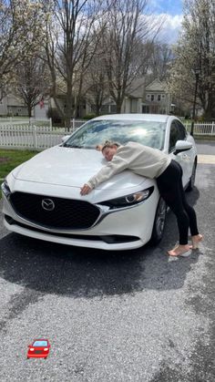 a woman leaning on the hood of a white car