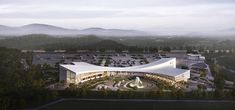 an aerial view of a large building surrounded by trees and mountains in the distance,