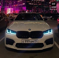 a white car parked on the side of a street next to tall buildings at night