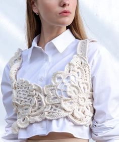 a woman wearing a white shirt and beige skirt with an intricate crochet collar