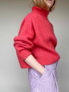 a woman with blonde hair wearing a pink sweater and purple pants