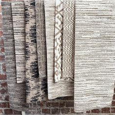 four different types of blankets hanging on a brick wall next to each other in front of a brick wall