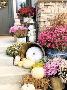 the front porch is decorated for fall with flowers and gourds in buckets