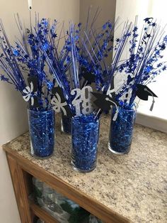 three blue vases with silver and black decorations on top of a marble countertop