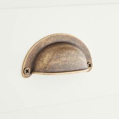 an antique brass door handle on a white painted cabinet with two screw holes in the middle