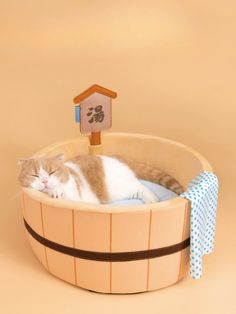 a cat is sleeping in a wooden basket