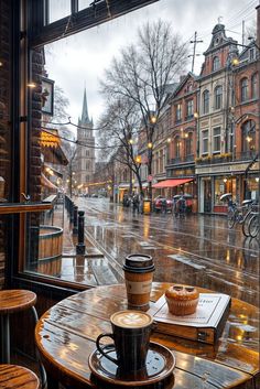 a cup of coffee sitting on top of a wooden table next to a large window