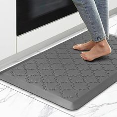 a person standing on a mat in front of an oven with their feet propped up