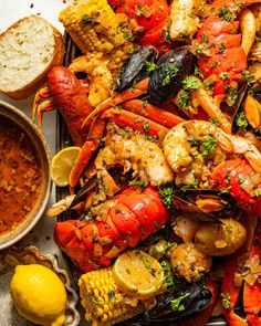 a platter with lobsters and corn on the cob next to some bread