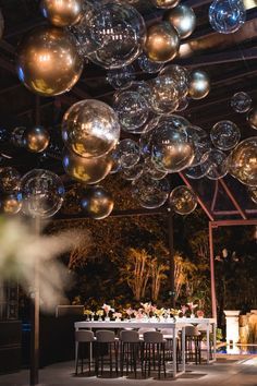 an outdoor event with large bubbles floating from the ceiling and tables set up for dinner