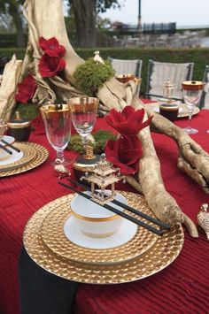 the table is set with red and gold plates