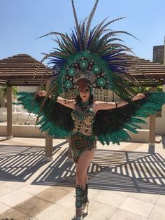 a woman in a green and black costume is posing with her arms spread out to the side