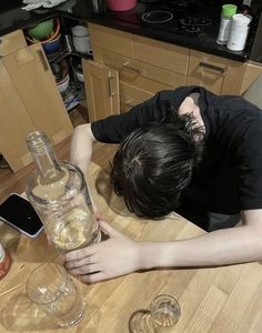 a man sitting at a table with two wine glasses and a cell phone in front of him