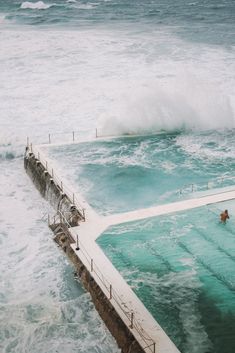 people are swimming in the ocean with waves coming up over the top of the pool