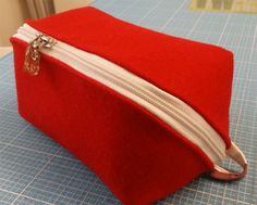 a red bag with white zippers sitting on top of a table