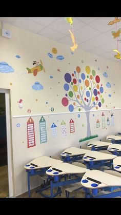 an empty classroom with desks and colorful wall decals on the walls, in front of a door