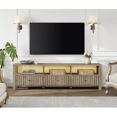 a large flat screen tv mounted on the wall above a wooden entertainment center with wicker furniture