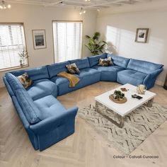 a large blue sectional couch sitting in a living room next to a white coffee table