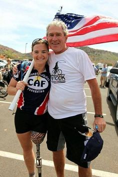 a man and woman standing next to each other with an american flag in the background