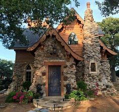 a small house made out of rocks with a wooden front door and windows on the side