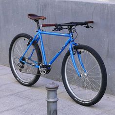 a blue bicycle parked next to a wall