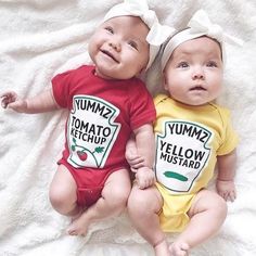 two baby babies laying on top of a bed wearing yummy tomato ketchup shirts