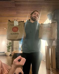 a man holding up a paper bag with a mcdonald's logo on it