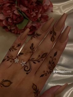 a woman's hand with henna tattoos on it and flowers in the background