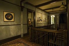 a hallway with wooden railings and framed pictures on the wall above it, along with an area rug