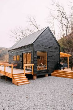 a small black cabin sitting on top of a gravel field