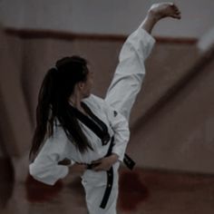 a woman is doing karate moves in the air with her hand up and one leg raised