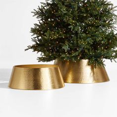 two gold planters sitting next to each other with lights on them and a christmas tree in the middle