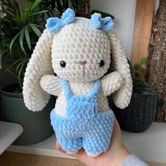 a crocheted white and blue stuffed animal in front of a potted plant