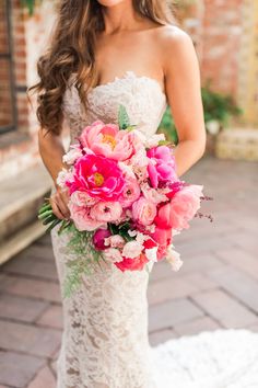 a woman in a wedding dress holding a bouquet of pink and white flowers on her shoulder