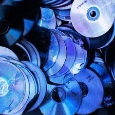 a pile of cds sitting next to each other on top of a tv screen in the dark