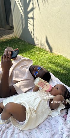 a woman laying on top of a blanket next to a baby