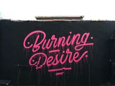 a black wall with pink spray paint that says burning desert on it and the words burning desert written in large letters