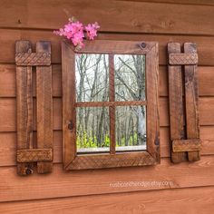 a window with wooden shutters and pink flowers