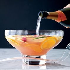 a pitcher pouring water into a glass filled with lemons and rhubarb