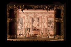 an elaborately decorated stage with chairs and paintings on the walls