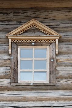 an old wooden window on the side of a log cabin with wood trimmings