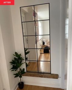 a mirror sitting on top of a wooden floor next to a plant in a vase