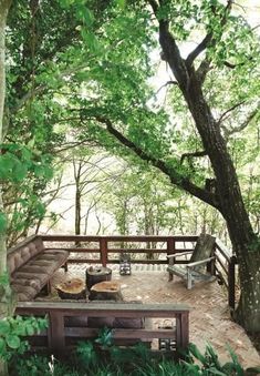 a wooden bench sitting on top of a lush green forest next to a large tree