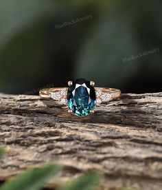 a blue diamond ring sitting on top of a piece of wood with leaves in the background