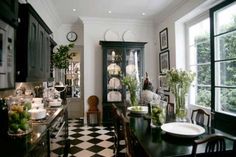 a black and white checkered floor in a dining room with lots of windows, cabinets and chairs